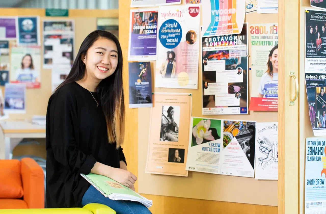 Student in front of a bulletin board covered with posters