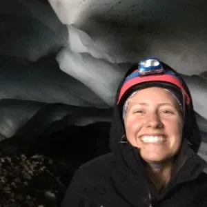 Smith student Molly Peek wears headlamp and stands surrounded by ice