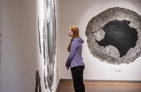 澳门葡京博彩软件艺术博物馆的一名学生，目不转睛地盯着右边墙上的艺术品