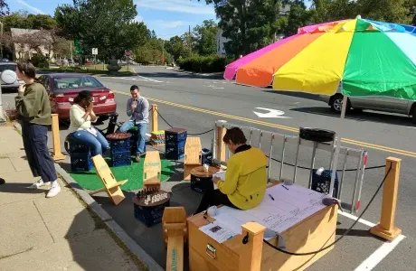 People relax in a portable park on the street, under an umbrella and surrounded by games
